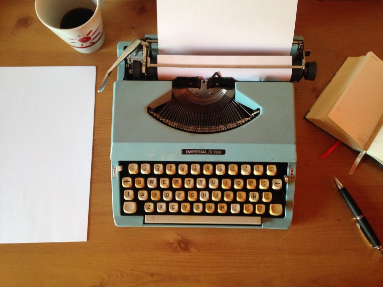 image of a typewriter, pen, paper, book and coffee cup